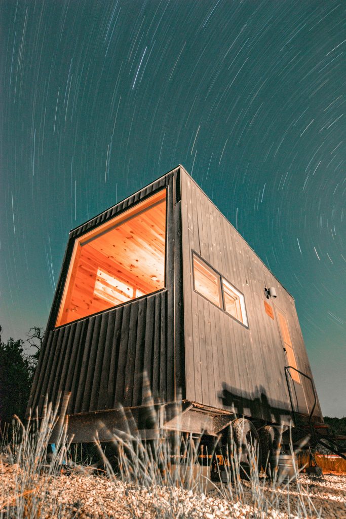 pexels-photo-5872466-5872466 Night view of a modern tiny house illuminated under a starry sky in Wimberley, Texas.